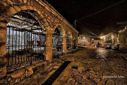 an old stone building with a gate at night at Κεντρικό κομψό ήσυχο στούντιο. in Ámfissa