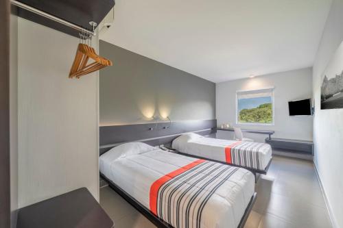 two beds in a small room with a tv at City Express Junior by Marriott Ciudad del Carmen Aeropuerto in Ciudad del Carmen