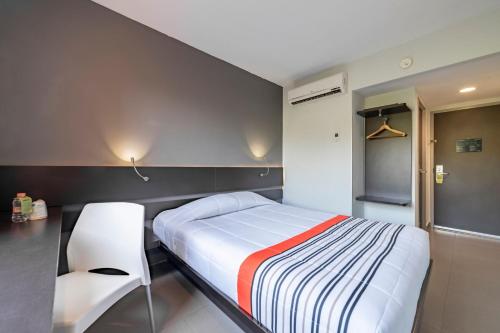 a bedroom with a bed and two white chairs at City Express Junior by Marriott Ciudad del Carmen Aeropuerto in Ciudad del Carmen