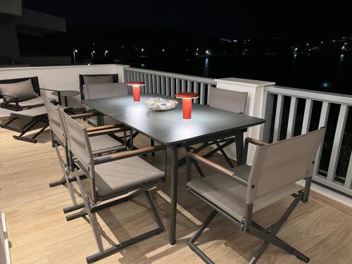 a table and chairs on a balcony at night at Sounio - Waterfront Luxury Spa Villa Pounta Zeza 170 sqm on Private Beach in Sounio