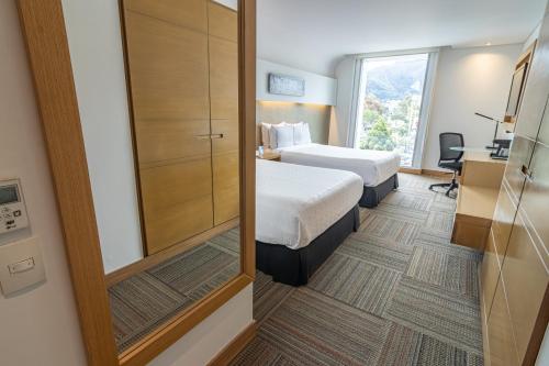 a hotel room with two beds and a mirror at Sonesta Hotel Bogotá in Bogotá