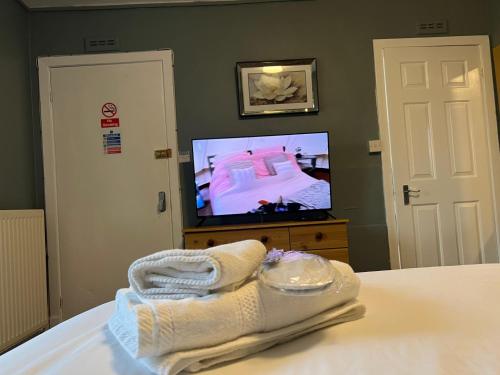 a bedroom with a bed and a tv and towels at SELF Check In Room Accommodation ONLY The Castle, Coldstream in Coldstream
