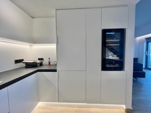 a kitchen with white cabinets and a black counter top at Sounio - Waterfront Luxury Spa Villa Pounta Zeza 170 sqm on Private Beach in Sounio