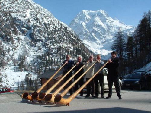 a group of men standing in front of a pile of baseball bats at Hotel du Pigne in Arolla