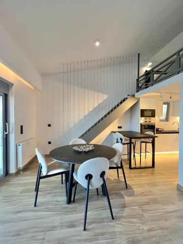 a dining room with two tables and chairs and a staircase at Sounio - Waterfront Luxury Spa Villa Pounta Zeza 170 sqm on Private Beach in Sounio