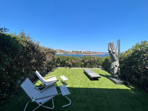 un giardino con due sedie e una panchina e un ombrellone di Sounio - Waterfront Luxury Spa Villa Pounta Zeza 170 sqm on Private Beach a Sounio