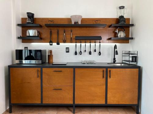 a kitchen with a counter with wooden cabinets and utensils at Pent house con terraza o departamento con balcón en el centro de oaxaca in Oaxaca City