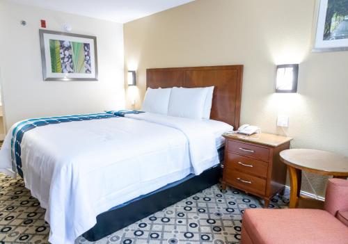 Pokój hotelowy z dużym łóżkiem i krzesłem w obiekcie Baymont by Wyndham College Park Atlanta Airport South w Atlancie