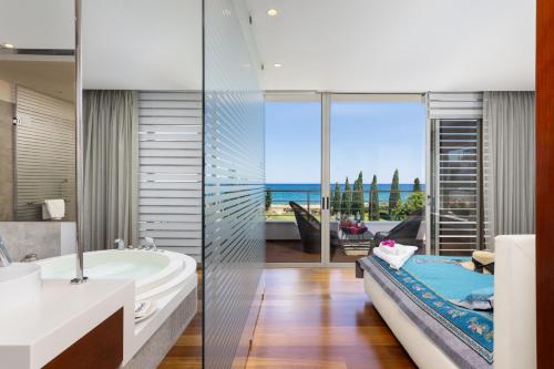 a bathroom with a tub and a large window at Annabel Beach Palace in Lachi