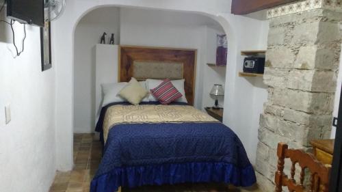 a bedroom with a bed with a blue comforter at Hotel Magdalena Colonial in Guanajuato