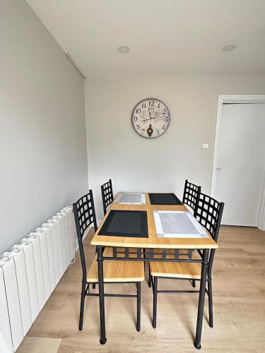 a dining room table with chairs and a clock on the wall at Tully's Home, Tulfarris Village, Wicklow in Blessington