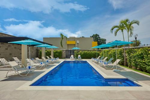 a swimming pool with chairs and umbrellas at City Express by Marriott Tapachula in Tapachula