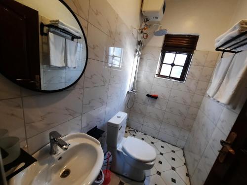 a bathroom with a sink and a toilet and a mirror at Deerwood Family Apartments, Bulenga in Bulenga