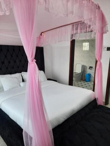 a bedroom with a bed with a pink canopy at Deerwood Family Apartments, Bulenga in Bulenga