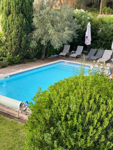 une piscine avec deux chaises longues et un parasol dans l'établissement Grande maison à teyran (34), à Teyran