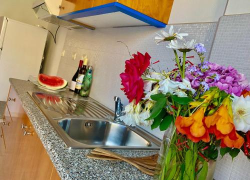 een vaas met bloemen naast een wastafel bij Nitsa's Apartments in Megálon Choríon
