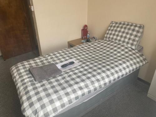 a bed in a room with a checkered bedsheet at The Old Post Office Public House & Hotel in Halifax