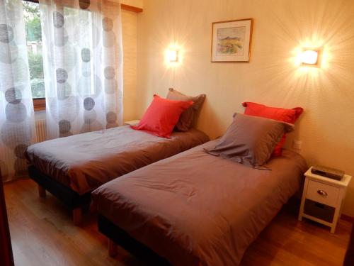 - une chambre avec 2 lits dotés d'oreillers rouges et d'une fenêtre dans l'établissement GITE KIENTZLER, à Ribeauvillé