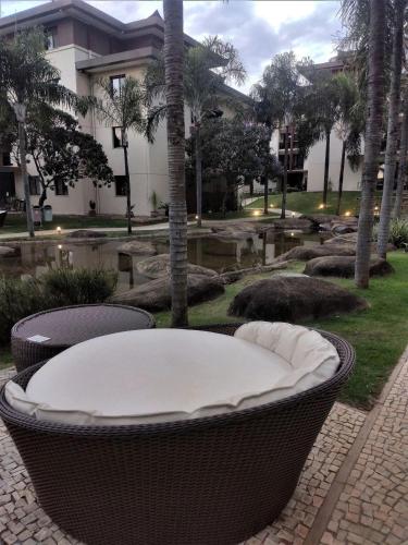 een rieten stoel met een tafel in een tuin bij L336 LB Apartamento aconchegante resort à beira lago in Brasilia