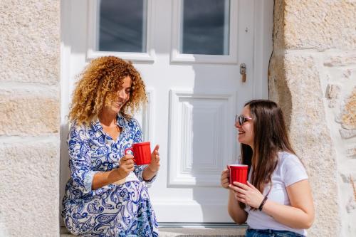 two women standing in front of a door holding red cups at CHALÉ in Alijó