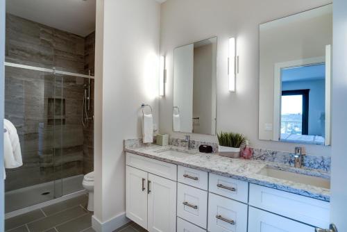 a white bathroom with two sinks and a shower at Modern Condo on South Slope in Asheville