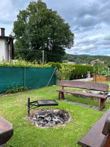 a park bench and a fire pit in the grass at Apartmama Lipová in Lipova Lazne