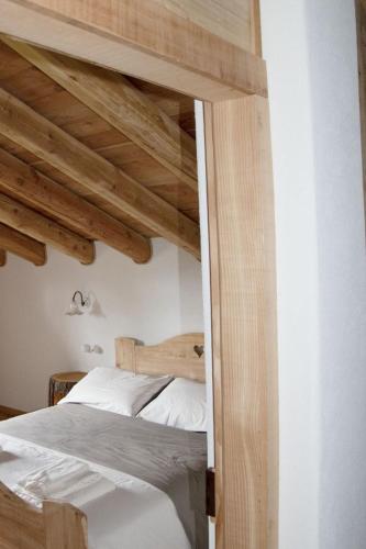 a bedroom with a bed and wooden ceilings at Baita dei Fovi in Baselga di Pinè