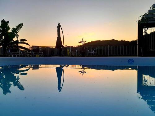 a swimming pool with a umbrella and a swimming pool at Pousada Pomar de Vassouras in Vassouras