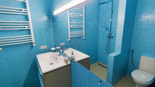 a blue tiled bathroom with a sink and a toilet at Fresh Accommodation in Rădăuţi