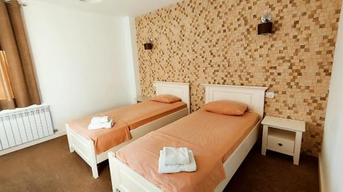 Habitación con 2 camas y pared de ladrillo en Fresh Accommodation, en Rădăuţi