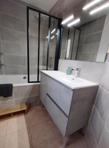 une salle de bain avec un lavabo, une baignoire et un miroir dans l'établissement Maison calme à proximité du Lac, à Savines