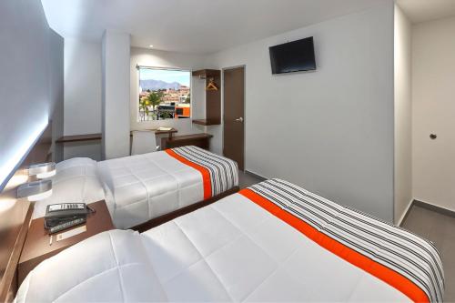 1 dormitorio con 2 camas y TV de pantalla plana en City Express Junior by Marriott Aguascalientes Centro, en Aguascalientes