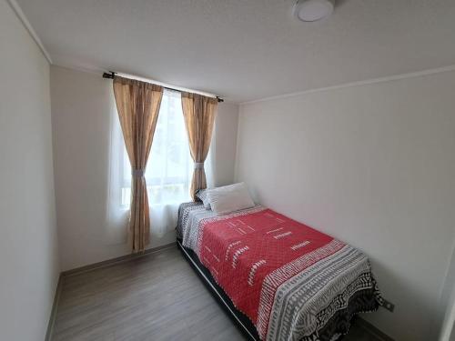 um pequeno quarto com uma cama e uma janela em Hermoso departamento con piscina em Arica