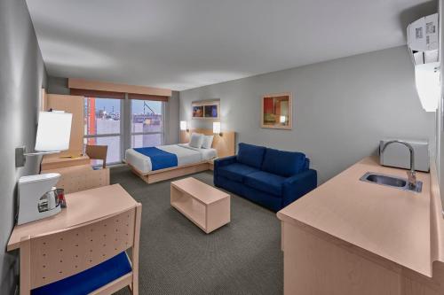 Habitación de hotel con cama y sofá azul en City Express by Marriott Apizaco, en Apizaco