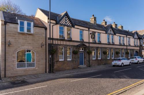 a building on a street with cars parked in front of it at The Queens Head, Parkside apartment 2 in Burley in Wharfedale