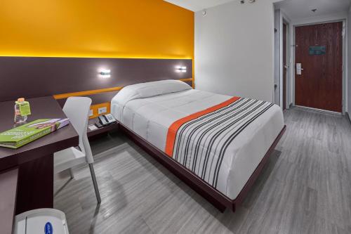 Bett in einem Zimmer mit einem Schreibtisch und einem Bett der Marke sidx sidx sidx. in der Unterkunft City Express Junior by Marriott Mexicali in Mexicali