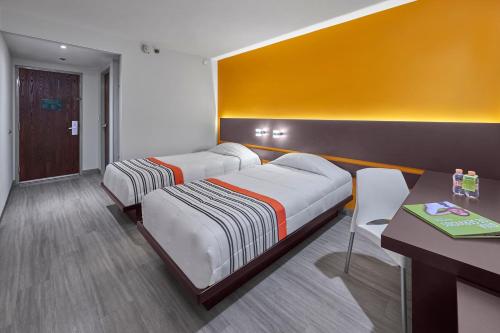 a bedroom with two beds and a desk and a table at City Express Junior by Marriott Mexicali in Mexicali