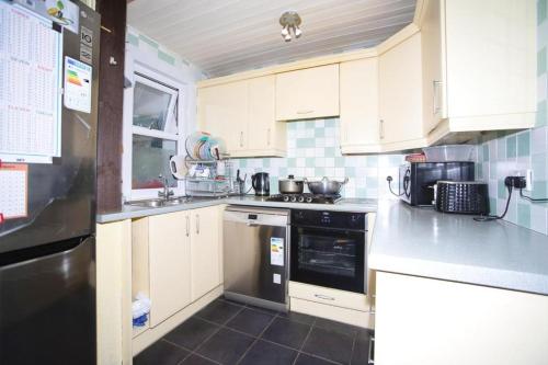 a kitchen with white cabinets and black appliances at 10 Valley Road, in Kent