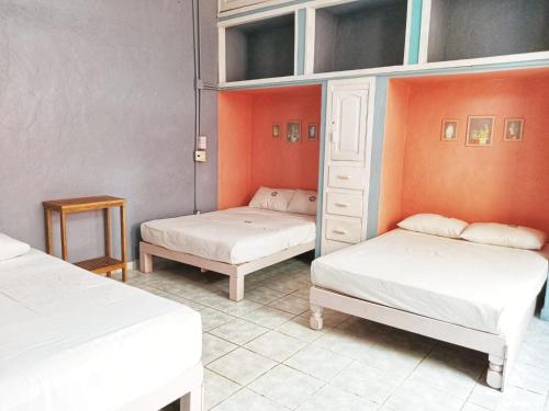 2 Betten in einem Zimmer mit orangefarbenen Wänden in der Unterkunft Riad Lola in Sayulita