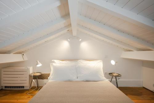 a bedroom with a bed with white walls and two lamps at Gateway House Studio Apartments in Guimarães