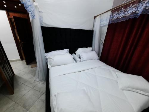 a bed with white sheets and pillows in a room at Deerwood Family Apartments, Bulenga in Bulenga