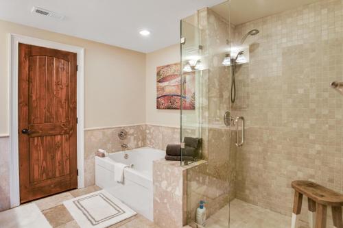 ein Badezimmer mit einer Badewanne und einer Dusche mit einer Glastür in der Unterkunft Magnificent S and W Building Condo in Asheville