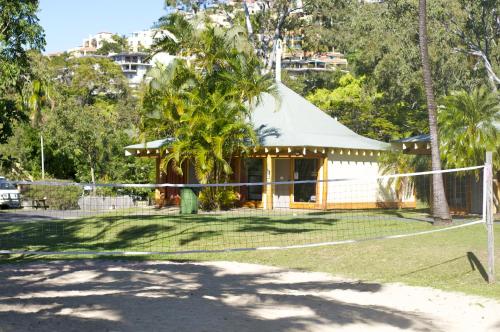 a green and white house with a fence and trees at Nomads Airlie Beach in Airlie Beach