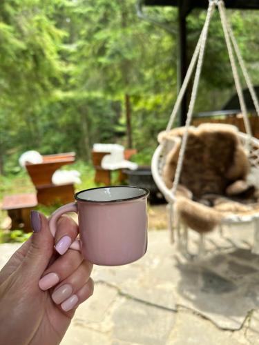 a person holding a cup in front of a swing at Chalet Látky in Látky