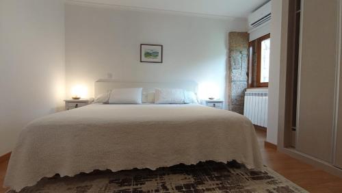 a white bedroom with a large bed with two lamps at Antiga Casa do Forno in Vidago