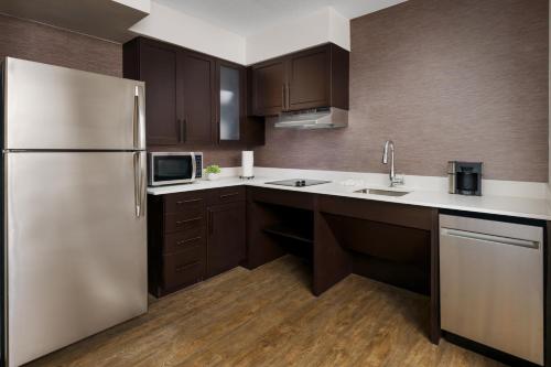 a kitchen with brown cabinets and a stainless steel refrigerator at Residence Inn Boston Franklin in Franklin