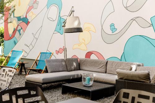 a living room with a couch and a mural at Motel One Köln-Mediapark in Cologne