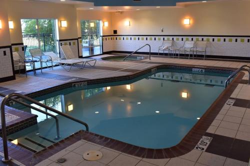 a pool in a hotel with tables and chairs at Fairfield Inn and Suites by Marriott Muskogee in Muskogee