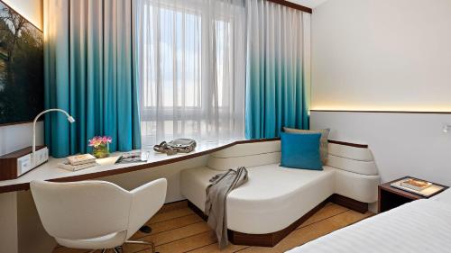 ケルステルバッハにあるHey Lou Hotel Frankfurt Airportのベッド、デスク、椅子が備わるホテルルームです。