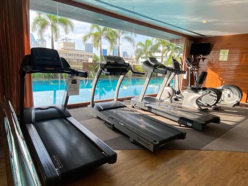une salle de sport avec trois vélos d'exercice et une piscine dans l'établissement Baan Nonzee Condo Kingsize bed Big room in Sathorn, à Bangkok